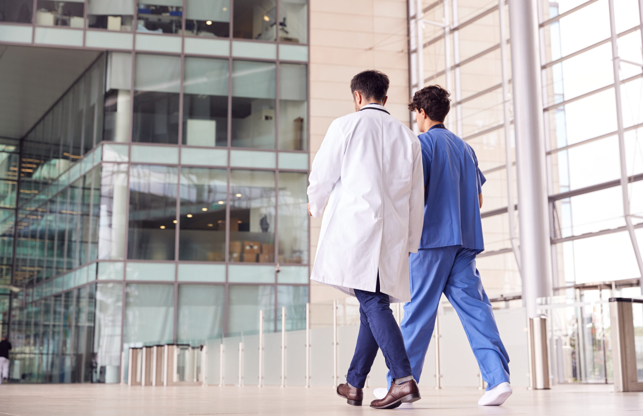 Rear,View,Of,Male,Medical,Staff,Talking,As,They,Walk